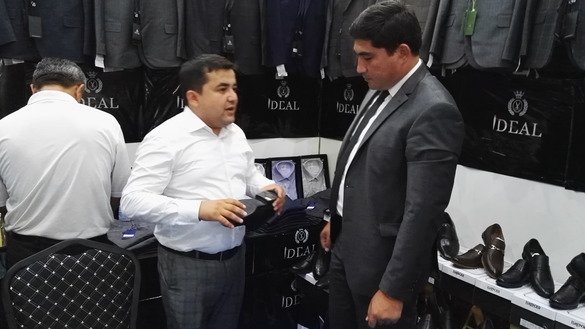Ўзбекистоннинг «Идеал» пойабзал ишлаб чиқариш корхонасининг раҳбари Акрам Каримов (чапда) Сўғд-2018 халқаро ярмаркасида меҳмонлар билан суҳбатлашмоқда, Хўжанд, 6 июль. (Негматулло Мирсаидов)