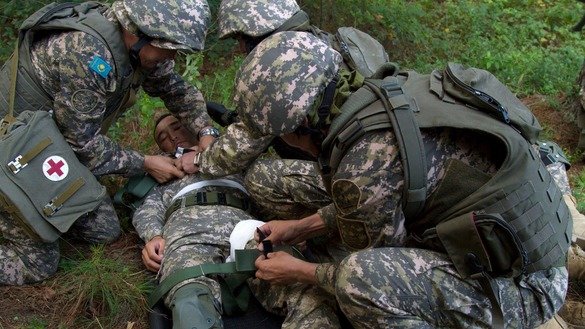 «Дашт бургути - 2018» машқлари давомида қозоғистонлик аскарлар «яраланган» шерикларини вертолётгача олиб бориш учун замбилга боғламоқда. (Аризона миллий гвардияси)
