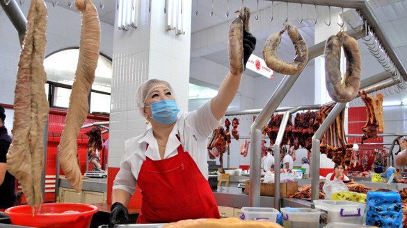 Продавщица национальных мясных деликатесов Айгуль Аденова в ожидании покупателей на Ошском рынке города Бишкека. На ее прилавке конские деликатесы: «казы» (мясо с полоской жира), «карта» (конская толстая кишка, вывернутая наизнанку, жиром внутрь) и «чучук» (сушеная колбаса). Бишкек, 13 августа. [Максат Осмоналиев]