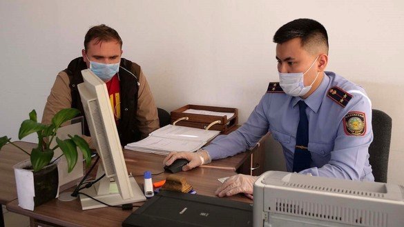 Миграция полицияси ходими фуқародан маълумот олмоқда, 25 август, Қозоғистоннинг Петропавловск шаҳри. (ИИВ)