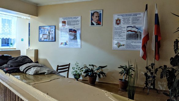 Портрет президента РФ Владимира Путина на стене средней школы им. И. И. Березенюка наряду с другой российской атрибутикой. Школы обязаны демонстрировать эти предметы после аннексии Крыма Россией в 2014 году. Поселок Коктебель, 26 февраля. [Евгений Гордиенко/«Каравансарай»]