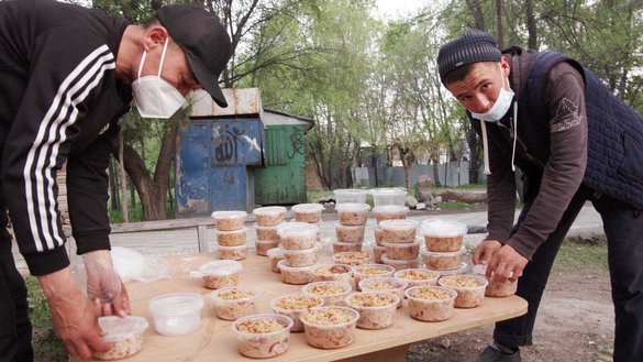 Работники мечети Келечек раскладывают плов и другие продукты питания по контейнерам. Еду раздадут постящимся мусульманам и нуждающимся. Бишкек, 27 апреля. [Максат Осмоналиев/«Каравансарай»]